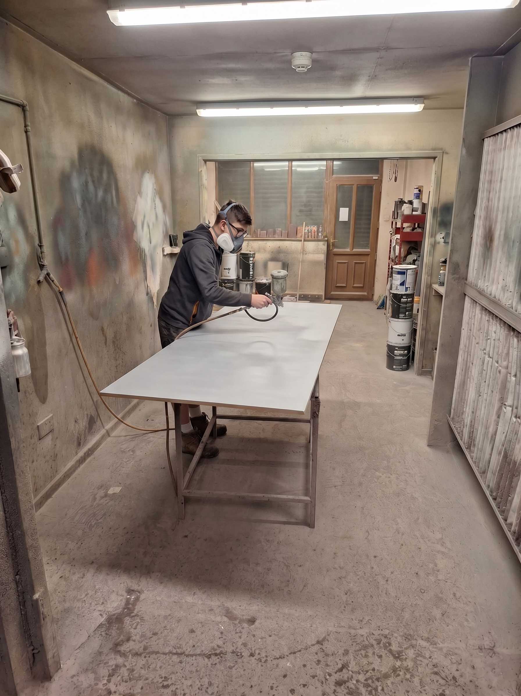 In-house spray booth applying a factory-grade finish to a joinery panel